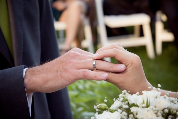 Mano tagliata della sposa che mette l'anello allo sposo durante la cerimonia nuziale