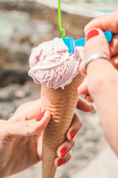 Mano tagliata di donna che tiene il cono di gelato all'aperto