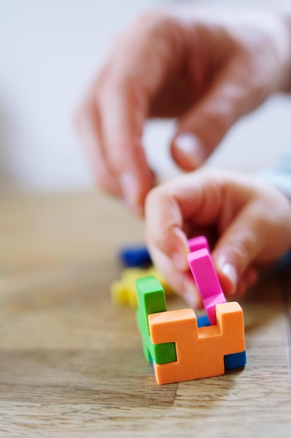 Mano tagliata di un bambino che gioca con i blocchi di giocattolo sul tavolo