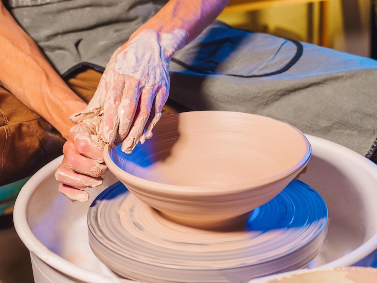 Foto mano tagliata di un ceramista che fa vasi usando la ruota di ceramica nel laboratorio