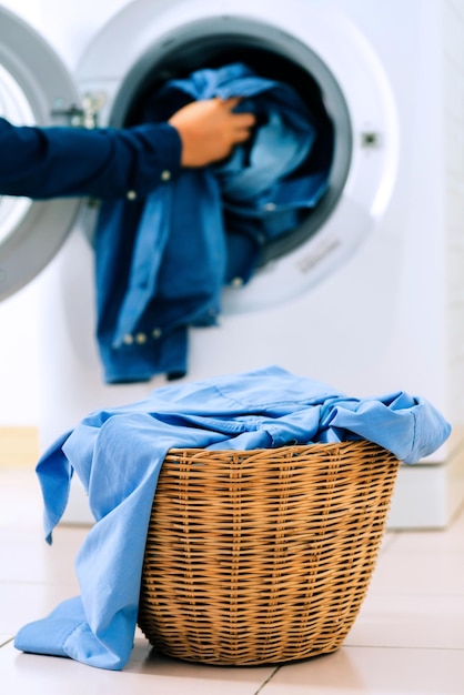 Mano tagliata di un uomo che mette i vestiti nella lavatrice