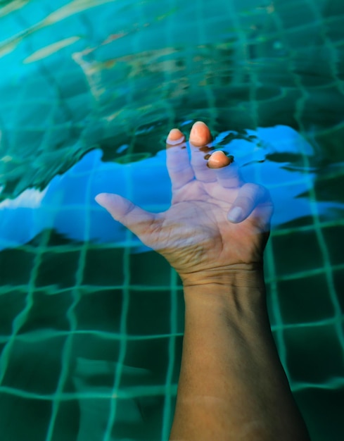 Mano tagliata di un uomo che nuota in piscina