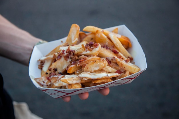 Mano tagliata di un uomo che tiene delle patatine fritte