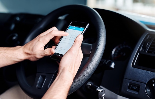 Mano tagliata di un uomo che usa un telefono cellulare in macchina