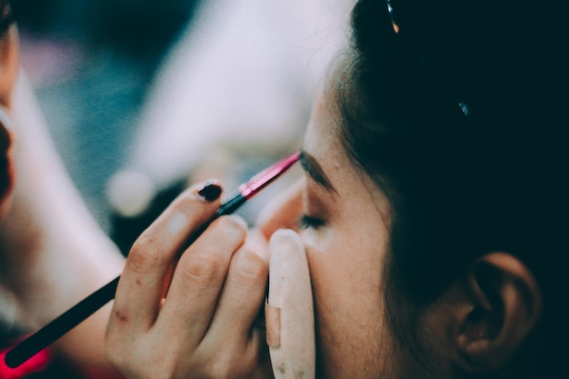 Mano tagliata di una donna che applica il trucco sul viso di una donna