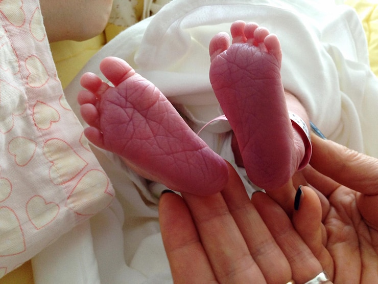 Foto mano tagliata di una donna che tiene le gambe del bambino
