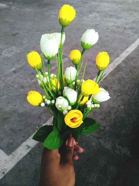 Mano tagliata di una donna che tiene un bouquet in strada