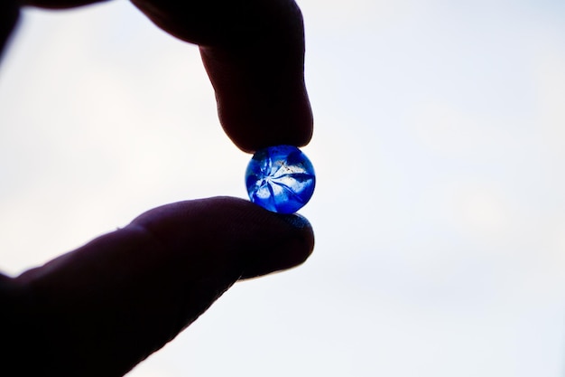 Mano tagliata di una persona che tiene un cristallo blu contro il cielo