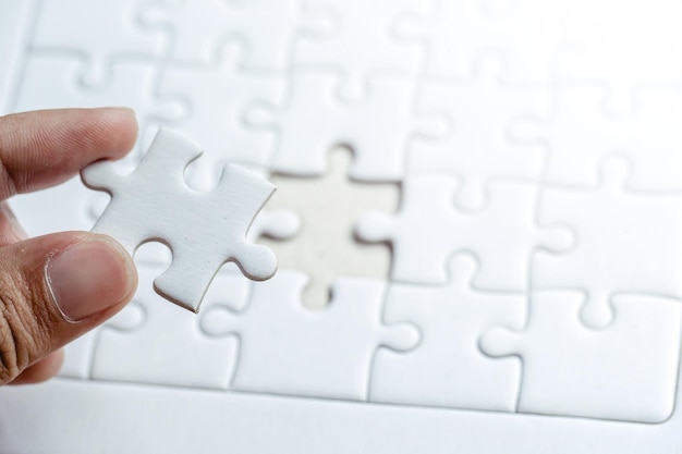 Mano tagliata di una persona che tiene un pezzo di puzzle