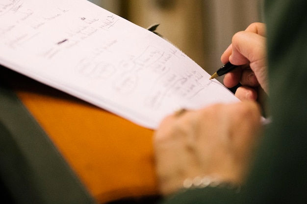 Mano tagliata di uno studente che scrive su carta