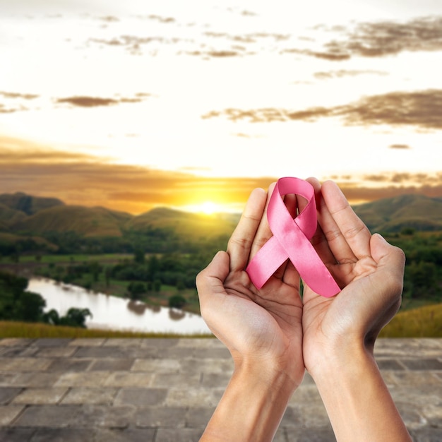 Mano umana che mostra un nastro rosa per la consapevolezza del concetto di consapevolezza sul cancro al seno