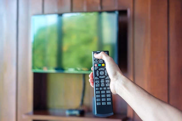 Mano usando il telecomando per regolare la Smart TV all'interno della stanza moderna a casa o in un hotel di lusso