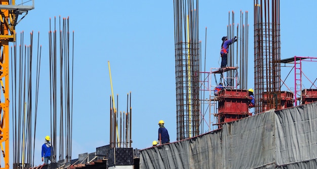 Manodopera che lavora in cantieri che hanno materiale industriale su un edificio alto e hanno un alto rischio in pericolo per la loro vita.