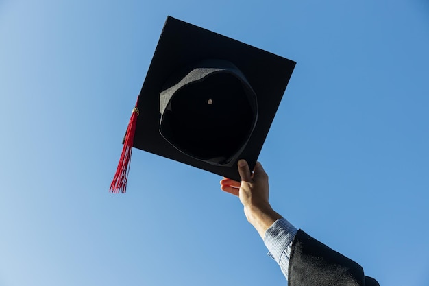 Mantello e cappello in mano femminile contro il cielo