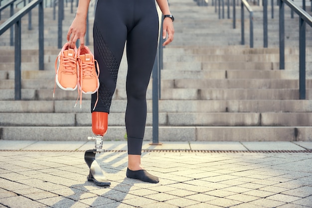 Mantenendo il mio corpo sano foto ritagliata di donna con protesi alla gamba in abbigliamento sportivo che trasporta