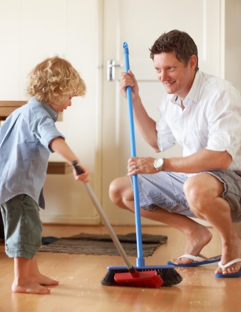 Mantenere le cose pulite Un padre e un figlio piccolo spazzano insieme la sabbia nella loro casa