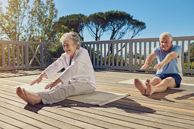 Mantenersi agile e agile Scatto di una coppia senior che fa yoga insieme nel loro patio esterno