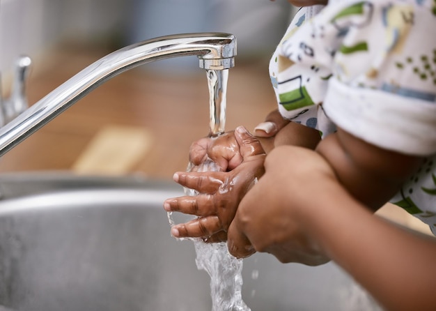 Manteniamo le mani pulite Inquadratura di un bambino e un genitore irriconoscibili che si lavano le mani a casa