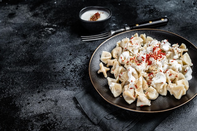 Manti turco con yogurt e salsa di pomodoro in un piatto Sfondo nero Vista dall'alto Copia spazio