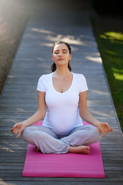 Mantieni la calma Inquadratura di una giovane donna incinta che fa yoga all'aperto