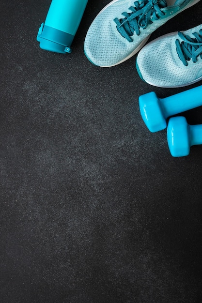 Manubri da ginnastica e bottiglia d'acqua su sfondo nero Concetto di allenamento e fitness Vista dall'alto