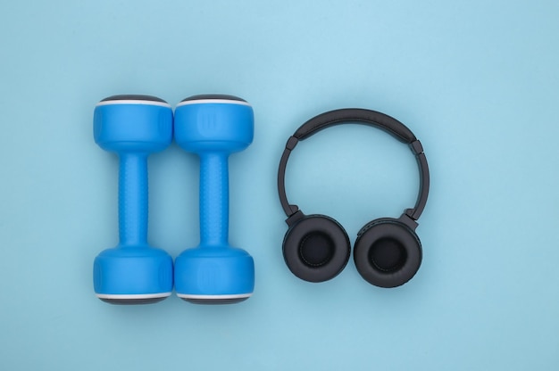 Manubri e cuffie stereo su sfondo blu. concetto di sport. Vista dall'alto