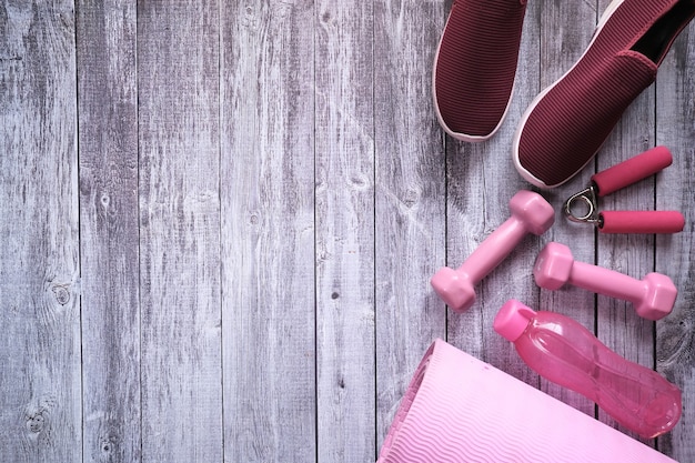 manubrio di colore rosa, scarpa e bottiglia su fondo in legno