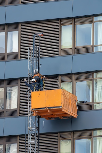 Manutentori su una culla sospesa o piattaforma elevatrice che eseguono lavori di riparazione sulla facciata