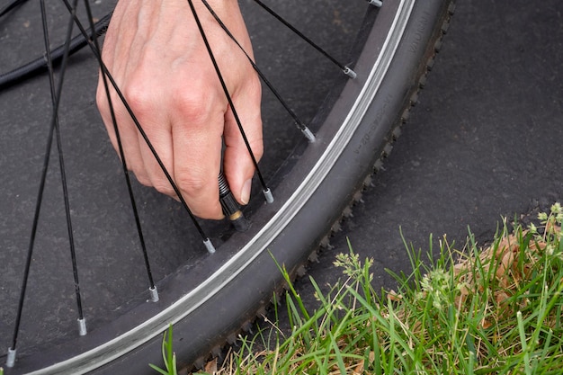 Manutenzione biciclette. Controllo della pressione dei pneumatici. Uomo che controlla la pressione dell'aria nei pneumatici e riempie l'aria in t