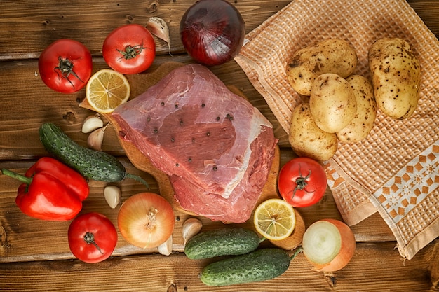 Manzo crudo con patate e verdure su assi di legno. Sopra la vista.