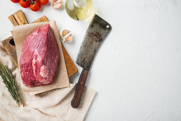 Manzo di marmo crudo su tagliere di legno con vecchio coltello da macellaio su sfondo bianco vista dall'alto piatto con spazio per la copia del testo