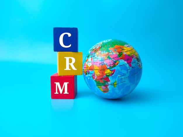 Mappamondo e cubo di legno colorato con parola CRM su sfondo blu