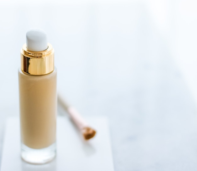 Marchio cosmetico glamour e concetto di cura della pelle trucco fondotinta bottiglia e pennello per il contorno su marmo trucco correttore crema bb come prodotto cosmetico per il design di vacanza del marchio di bellezza di lusso