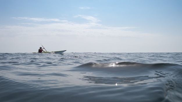 Mare aperto. Un uomo sta navigando su un kayak in background