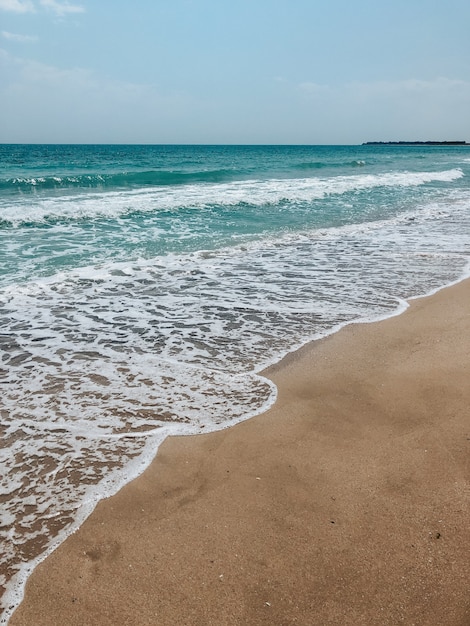 mare blu acquamarina onde linea soleggiata spiaggia di sabbia. morbida onda di schiuma oceanica.