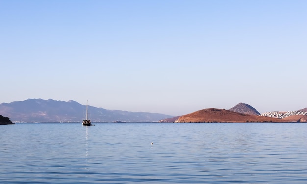 Mare blu una barca isole e montagne Paesaggio marino tranquillo e natura costiera sullo sfondo