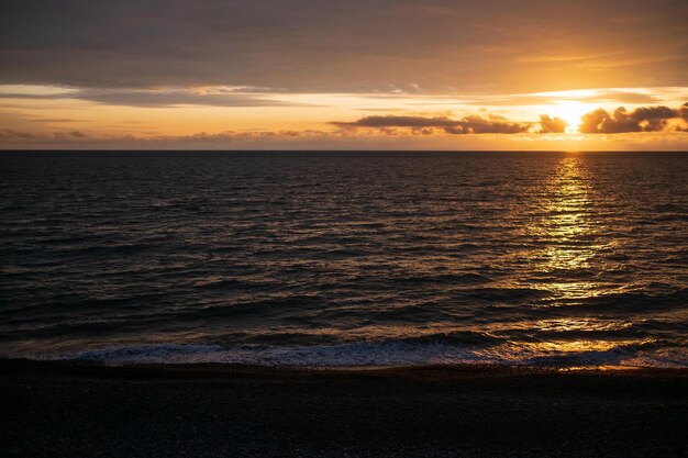 Mare calmo con cielo al tramonto e sole attraverso le nuvole