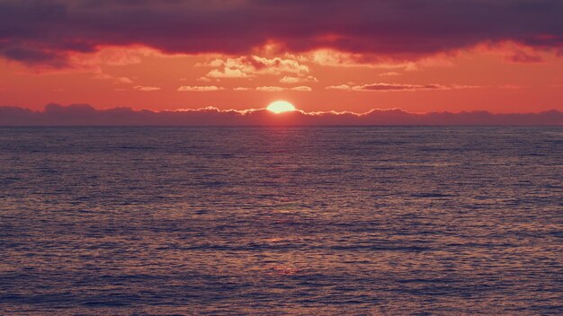 Mare con la luce del sole sullo sfondo al tramonto tramonto arancione e rosso sopra il mare fantastico tramonto naturale