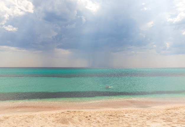 Mare estivo bellissimo di spiaggia tropicale esotica. Verde smeraldo del mare e cielo azzurro brillante con nuvole con luce solare. Paesaggio marino estivo, acqua dell'oceano turchese, isola idilliaca o banner sulla spiaggia