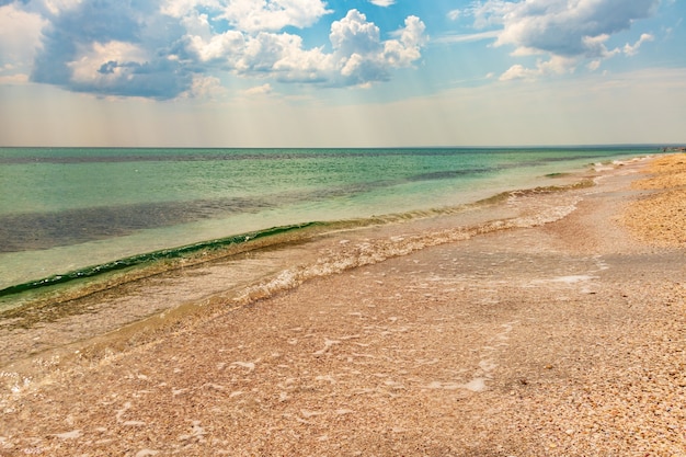 Mare estivo bellissimo di spiaggia tropicale esotica. Verde smeraldo del mare e cielo azzurro brillante con nuvole con luce solare. Paesaggio marino estivo, acqua dell'oceano turchese, isola idilliaca o banner sulla spiaggia