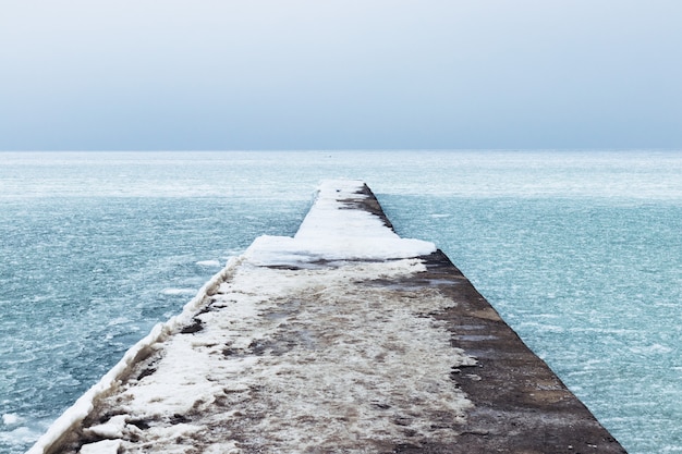 Mare ghiacciato e molo coperto di neve