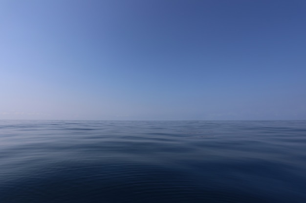 Mare liscio e cielo blu di giorno con aria limpida.