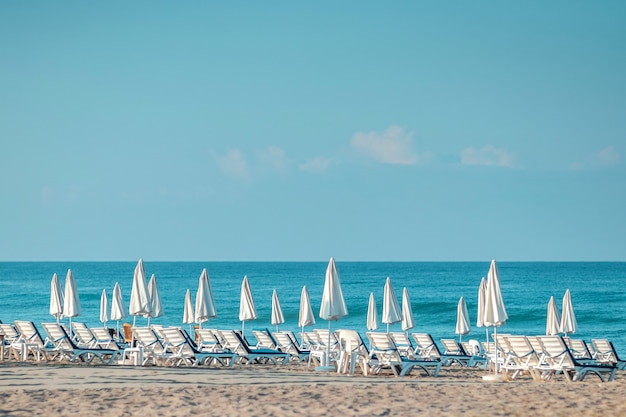 Mare mattutino, spiaggia, lettini vuoti per i vacanzieri. Concetto di vacanza.