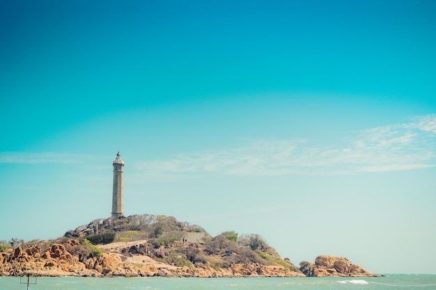 Mare natura vista panoramica paesaggio sfondo Oceano scogliere rocciose isola boscosa Cielo azzurro chiaro Faro sulla cima della montagna Segnale avvertire i marinai naufragio viaggio concetto speranza scopo della vita