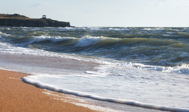 Mare surf grande rottura dell'onda sulla costa e sul promontorio con padiglione a distanza