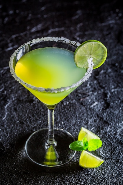 Margarita classica verde con lime fresco su roccia nera