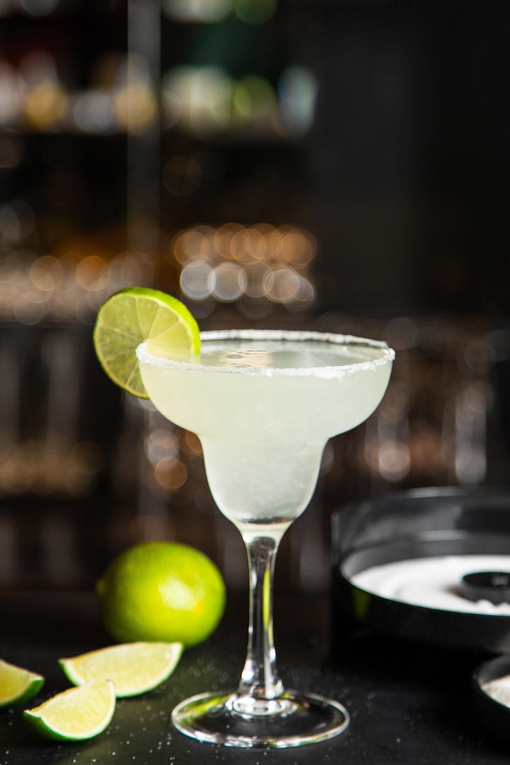 Foto margarita in un bicchiere con lime in un bicchiere su sfondo scuro noci e verdure