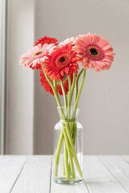 Margherite rosse e rosa della gerbera in vaso sulla tavola, stile minimo Copia spazio