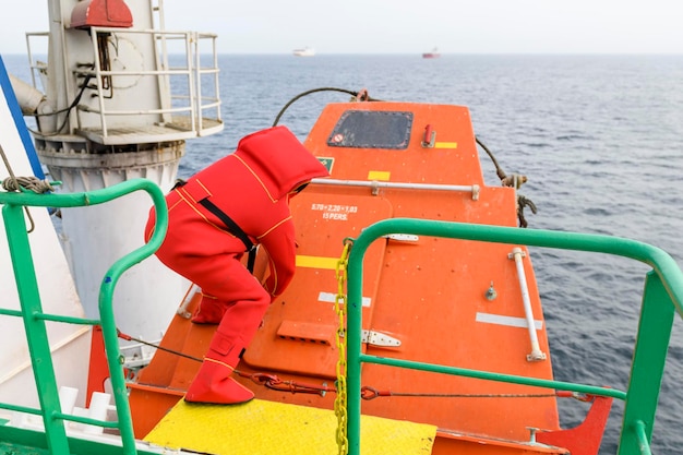 Marinaio che indossa la tuta di immersione sulla stazione di radunamento Abbandona l'esercitazione della nave barca a caduta libera nave da carico