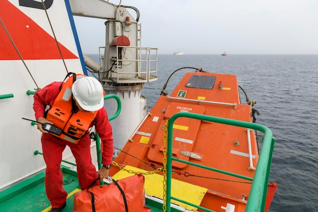 Marinaio che indossa un giubbotto di salvataggio con radio VHF sulla stazione di Muster Abbandona l'esercitazione della nave barca a caduta libera